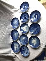 All twelve blue-and-white Royal Copenhagen plates laid out on white tablecloth