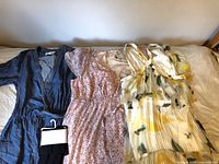 All five garments laid out on bed showing styles and colours