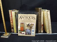 Group shot of eight visible books including The Collector's Encyclopedia of Antiques, Turner, Lithography, Notman, Pinakothek, Presciliano Silva with measuring stick for scale