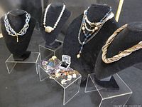 Front view of four necklaces on busts and tray of assorted jewellery