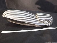 Full left side view of wooden raven mask with measuring tape