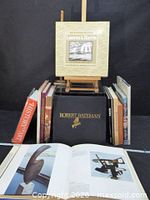 Group of art books including Robert Bateman, Lawren S. Harris, History of Art, Monet, Van Gogh, Matisse; open page shows sculpture