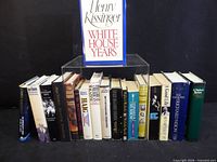 Full row of approximately 18 hardcover books with Henry Kissinger volume displayed on stand