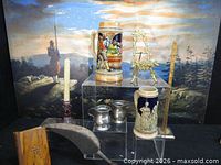 Group shot showing both steins, pewter mugs, brass figurine, sickle, wooden plaque