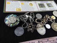 Group shot showing jewelry pieces, coins and reproduction penny display card