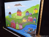 Full view of painted canvas showing village scene and measuring tapes indicating size