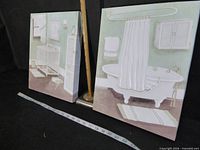 Both canvas bathroom scene prints displayed upright with ruler and tape for scale