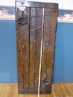 Full view of reclaimed wood door panel showing dimensions tape and iron strap