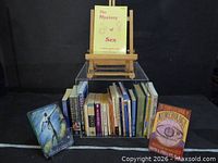 Overall lot showing books on acrylic riser; The Mystery of Sex and The Complete Book of Numerology displayed