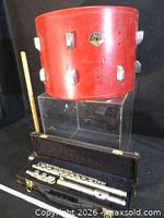 Drum shell on stand with ruler and closed flute case beneath