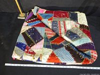 Quilt folded on table showing patchwork and ruler for scale