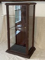 front angled view of wooden display case showing glass panels and shelves
