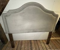 Front view of grey upholstered headboard with wood legs
