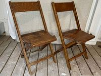 Pair wooden folding chairs standing open on wooden floor