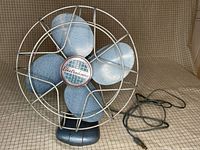 Front view of metallic blue Electrohome four-blade fan with wire cage and cord