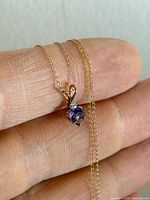 Full view of necklace draped on fingers showing chain and pendant