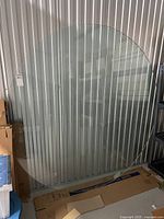 Full view of large round glass tabletop leaning against wall