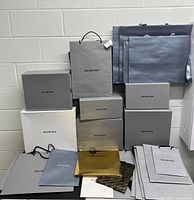 Stack of Balenciaga boxes with various shopping bags in front