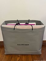 Large grey Balenciaga paper shopping bag with rope handles, holds other bags
