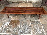 Full view of afromosia slat bench on stone floor