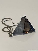 Front view of pendant showing brushed metal half and faceted smokey quartz stone, chain visible