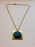 Full view of gold-tone necklace with square green enamel pendant