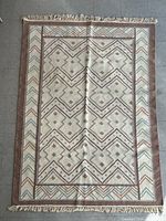 Full view of wool area rug showing pattern, colors and fringe