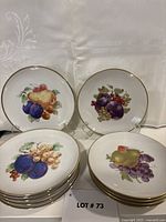 Front view showing assorted fruit designs and gold rims on stacked and displayed plates