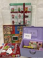 Group shot of all items: Christmas craft kit, Melissa & Doug stamp set, purple stamp chest, Peanuts Matching game