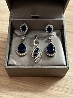 Necklace pendant and earrings in presentation box showing stones and settings