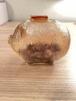 Side view of amber glass pig bank showing texture and pennies inside