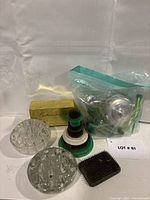 Group shot of entire lot showing glass frogs, stacked metal pin frogs, square kenzan, boxed item and bagged contents