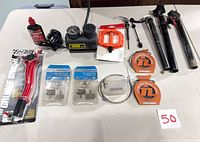 All items laid out on table including compressor, pedals, cables, brake pads, skewers, seatposts, brush, lubricant