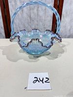 Front view of blue opalescent ruffled basket with twisted handle and plum rim