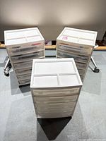 Three white plastic rolling carts on casters