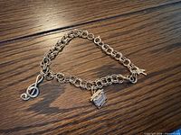 Full view of 10k gold charm bracelet showing all three charms on wood surface