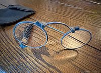 Folding silver lorgnette spectacles and leather case on wooden surface