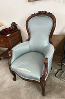 Front view of Victorian style arm chair showing carved frame and damaged upholstery