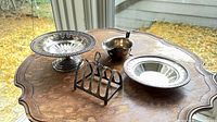 All four silver items on table: footed bowl, shallow bowl, toast rack, gravy jug