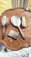 Group shot of hand mirror, two brushes, cigarette case on table