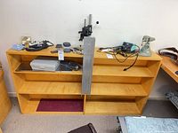 Front view of light wood bookcase with three shelves, bracket and other items on top (not included)