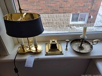 All four brass items on window sill: bouillotte lamp, inkwell stamper, candle holder with candle, snuffer