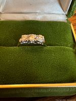 Front view of 18K gold ring with three diamonds in case