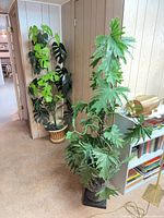 Two tall faux plants in respective pots