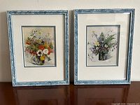Both framed floral prints side by side on surface