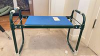 Overall view of green metal folding kneeler bench with blue pad