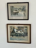 Two framed Paul Caron prints hung on wall