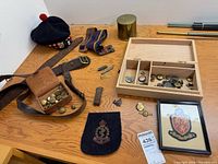overview showing beret, belt, leather pouch with buttons, web strap, framed crest, felt badge, key fob, wooden box and brass container