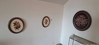 Wall view of three oval needlepoint artworks