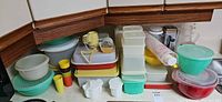 Overview of stacked Tupperware containers, mixing bowls, strainer set and utensils